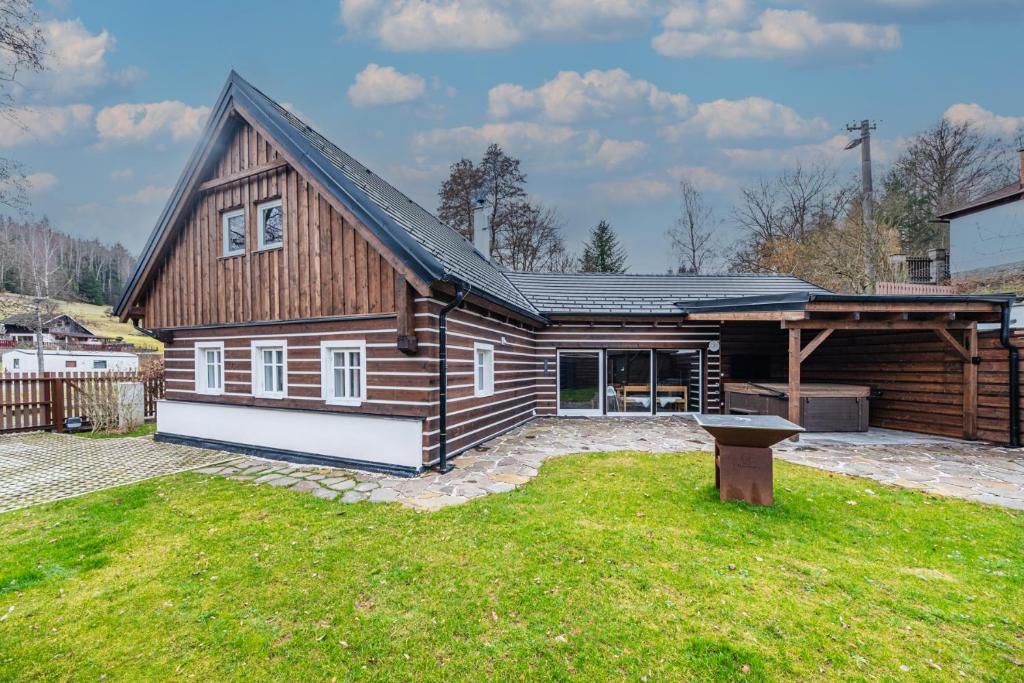 ein großes Holzhaus mit einem Rasenhof in der Unterkunft Roubenka50 in Jičín