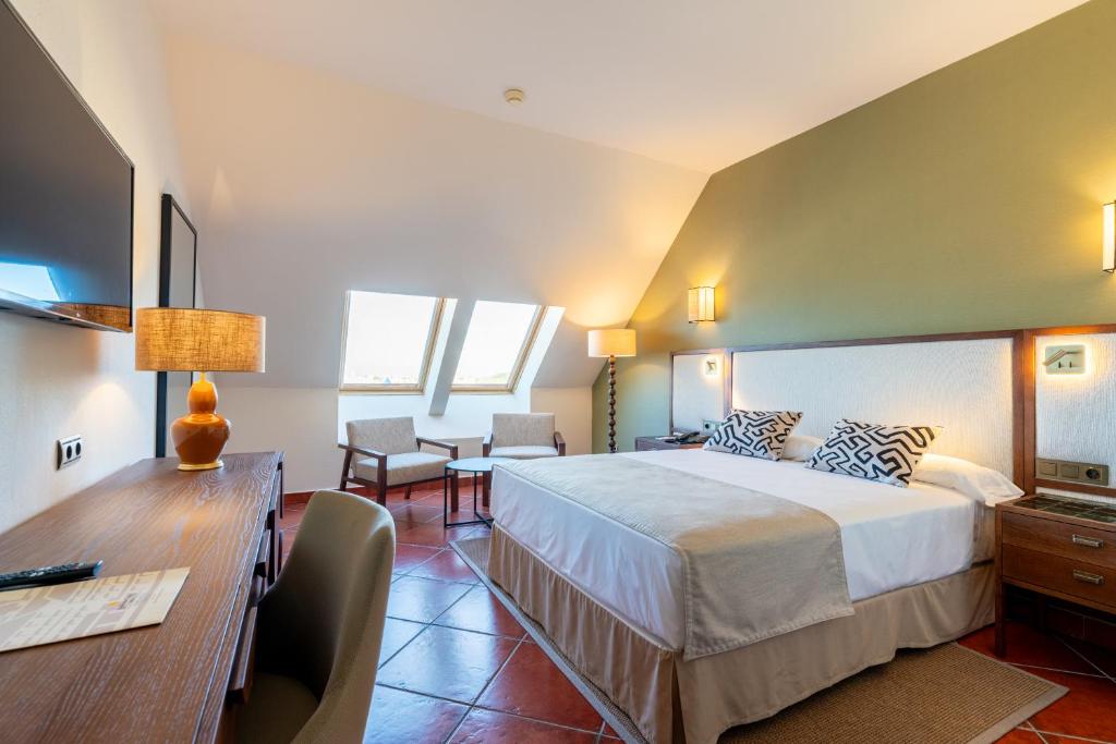 a hotel room with a large bed and a desk at Puerto Antilla Grand Hotel in Islantilla