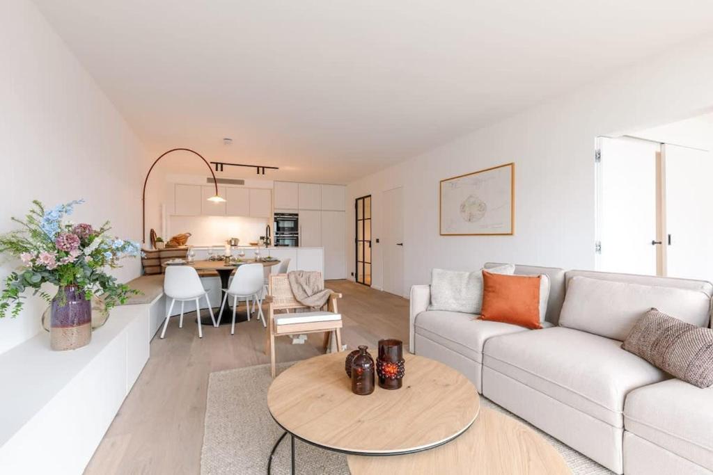 a living room with a couch and a table at Huswell - Renovated apartment with sea view and parking in Knokke-Heist