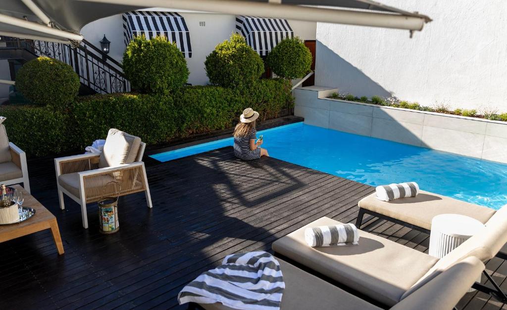 a woman sitting on a deck next to a swimming pool at Lemoenkloof Boutique Hotel in Paarl