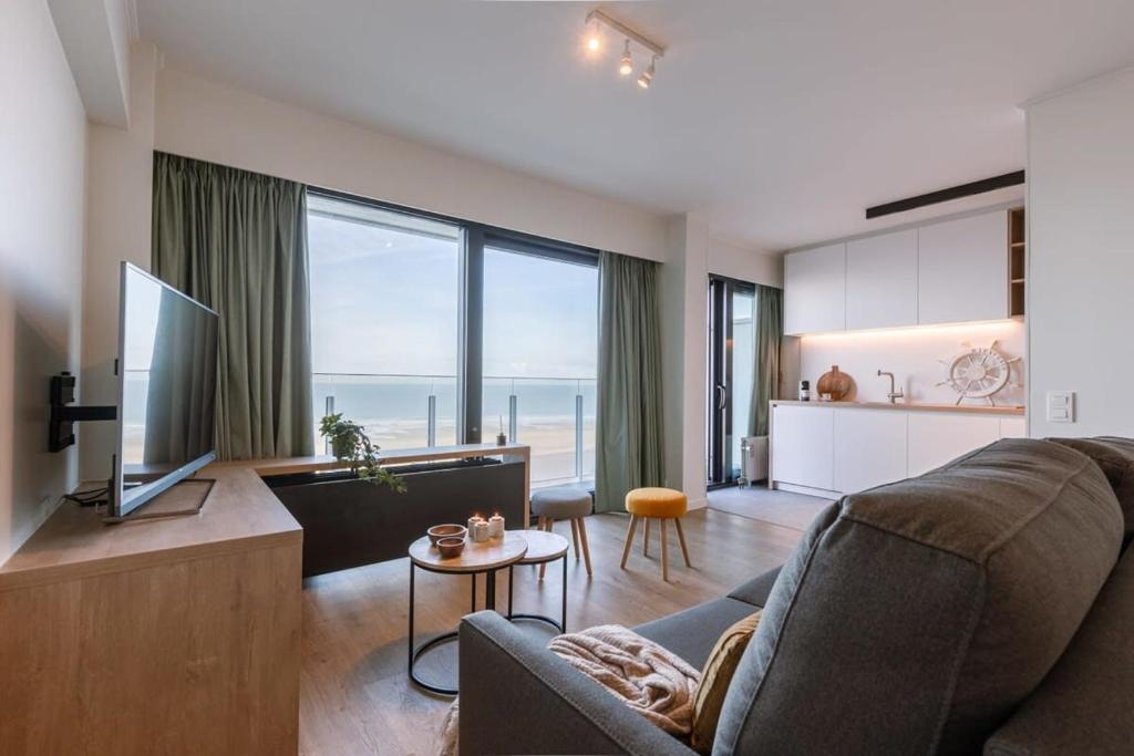 een woonkamer met een bank en een groot raam bij Huswell - Cosy apartment with terrace overlooking the sea in Middelkerke