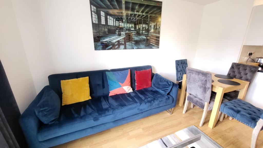 a living room with a blue couch with colorful pillows at Garland Central City Apartment London 2 in London