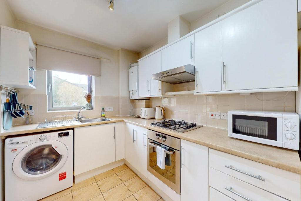 a kitchen with white cabinets and a washer and dryer at Modern 1 BD Apartment in London - 5 min to Station in London