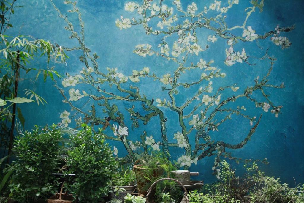 a blue wall with a tree with white flowers at 弱水咖啡国际青旅Only Cafe and Backpacker in Chongqing