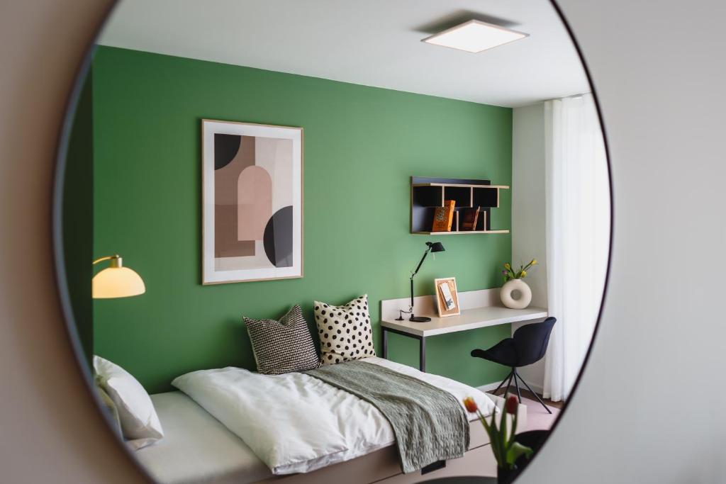 a green bedroom with a bed and a desk at The Circus Living in Berlin