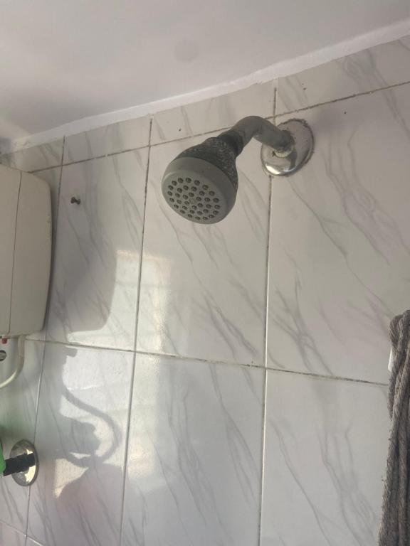 a shower with a shower head on a white tile floor at Boho connection in Mumbai
