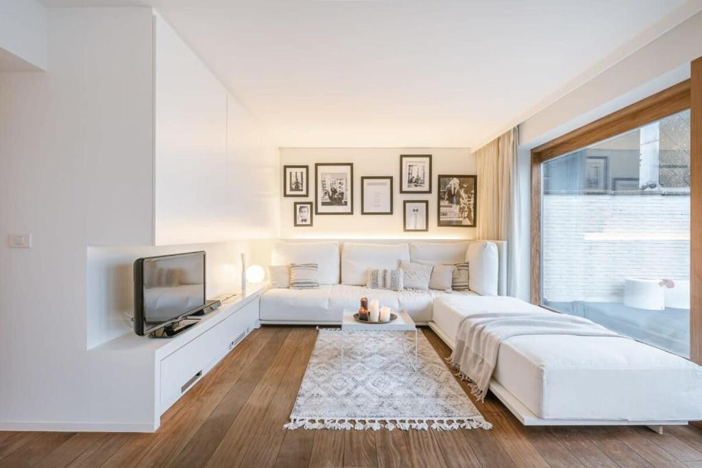 um quarto branco com uma cama grande e uma televisão em Modern renovated apartment with terrace and parking em Knokke-Heist