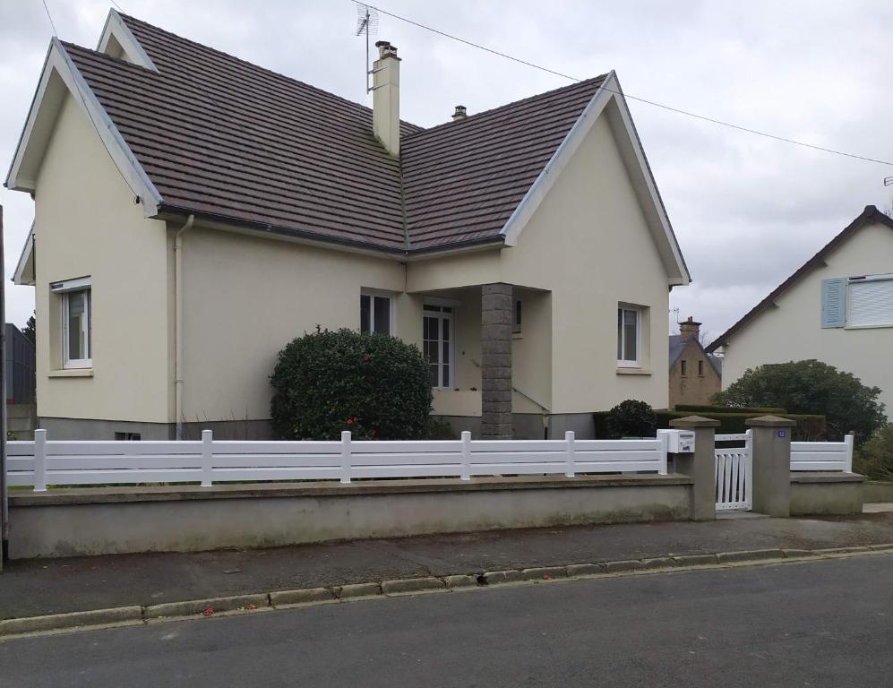 una casa blanca con una valla blanca en La Cotentine, en Coutances
