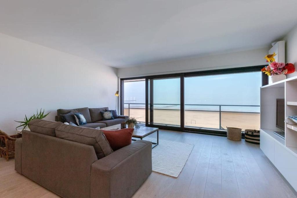 ein Wohnzimmer mit einem Sofa und Strandblick in der Unterkunft Luxurious and modern family apartment with incredible view over the beach in Knokke-Heist
