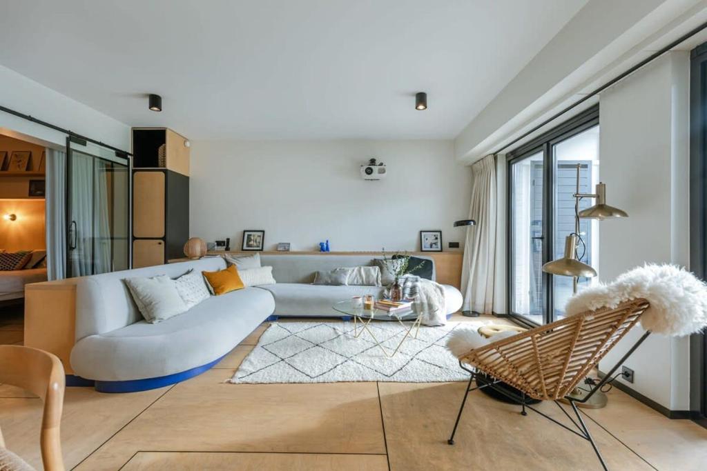 ein Wohnzimmer mit einer weißen Couch und einem Stuhl in der Unterkunft Apartment with garden at the seaside in Knokke in Knokke-Heist