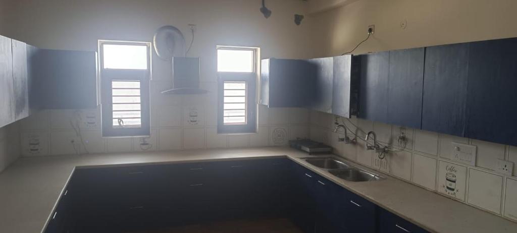 uma cozinha com um lavatório e duas janelas em RidgeWay Stay em Faridabad