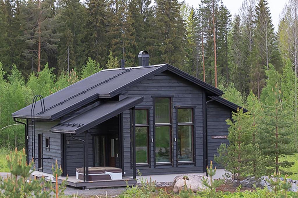 una cabaña negra en medio de un bosque en Villa Luoteistuuli - 8+2 hlö, Luoteis-Himos Ski-in/out, 88m² + 30m², en Jämsä