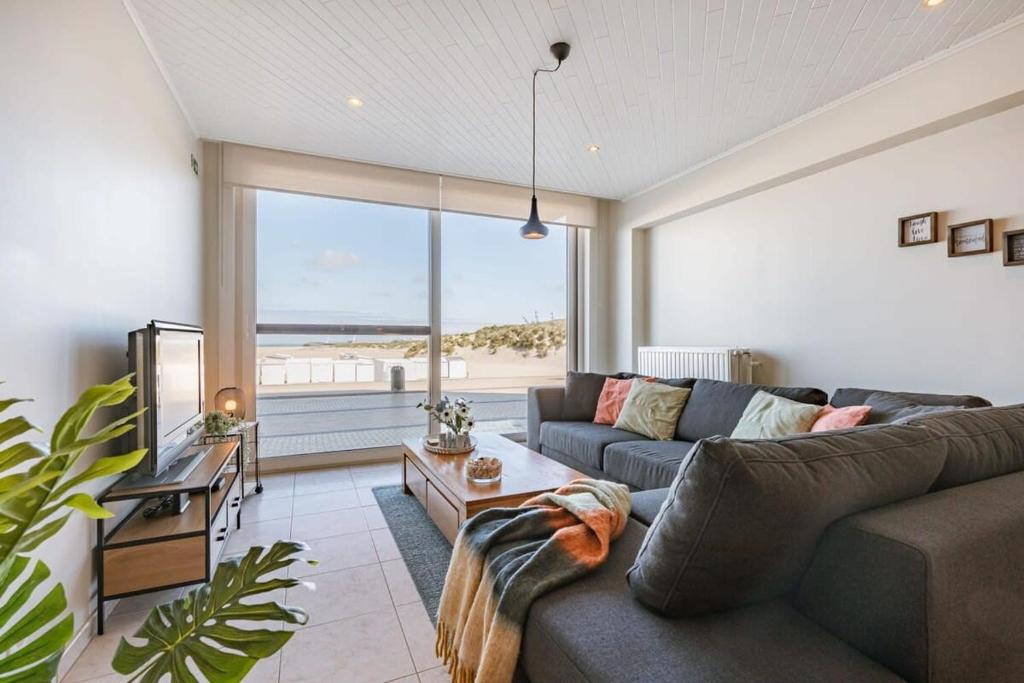 a living room with a couch and a large window at Beachfront apartment in Zeebrugge in Bruges