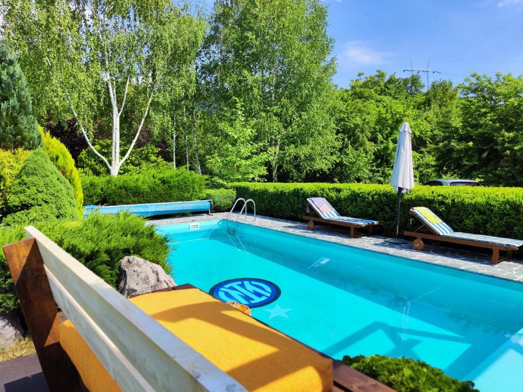 a swimming pool in a garden with a patio furniture and an umbrella at Luxury Resort Riverfront with Pool&Sports in Višegrad