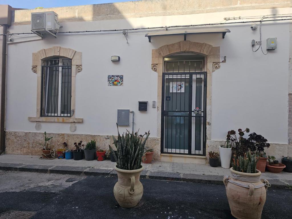 ein weißes Gebäude mit einer Tür und einigen Topfpflanzen in der Unterkunft Regina Lucia casa vacanze in Syrakus