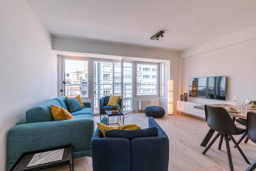 Una sala de estar con un sofá azul y una mesa. en Huswell - Lovely apartment with lateral sea view and parking, en Ostende