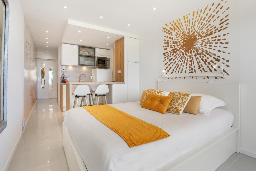 - une chambre blanche avec un grand lit et une cuisine dans l'établissement La Dolce Vita naturiste Port Nature, au Cap d'Agde
