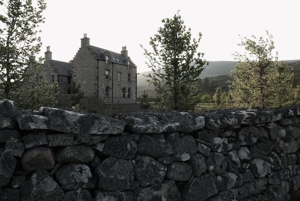 an old stone wall in front of a building at Gairnshiel lodge - Unique & exclusive lodge next to the castle in Ballater