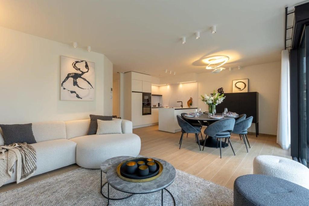 a living room with a white couch and a table at Modern apartment located on the square of De Panne in De Panne