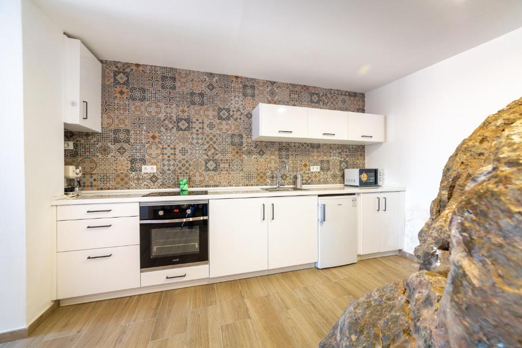 a kitchen with white cabinets and a tile wall at AlmeriaSuite Roca 2 Mojacar in Mojácar