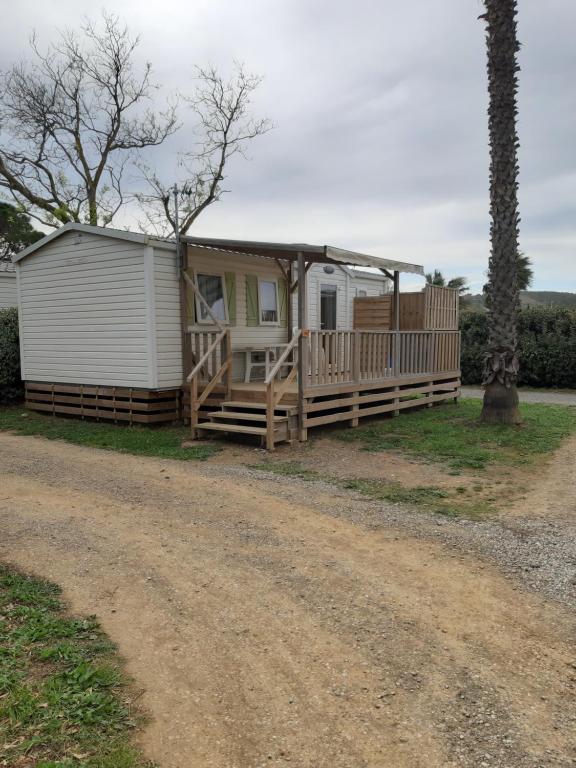 a mobile home with a porch and a dirt road at camping le novela in Port-la-Nouvelle
