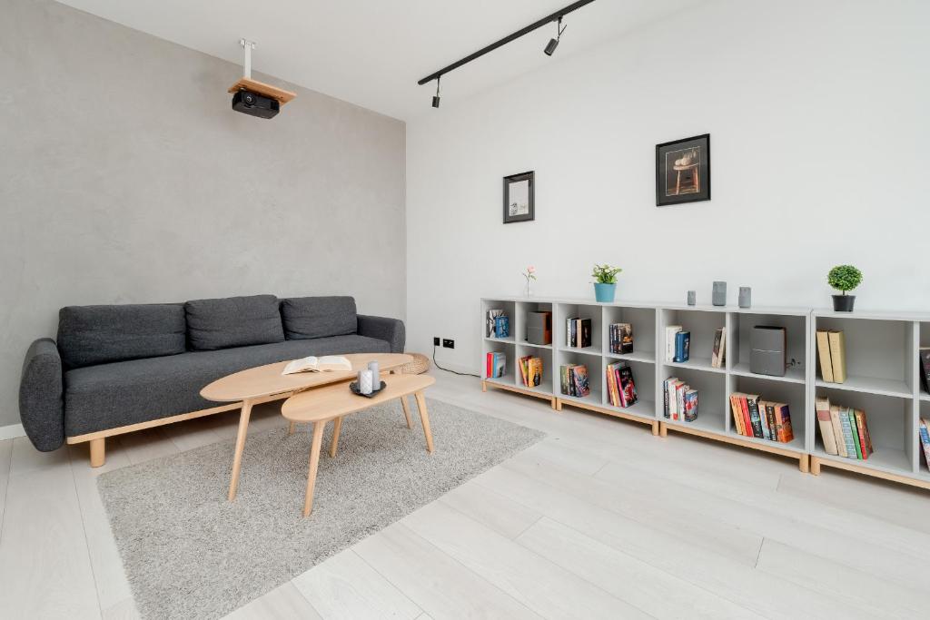 a living room with a couch and a table and bookshelves at Bright Apartment with Balcony Close to the Poniatowski Park Łódź by Renters in Łódź