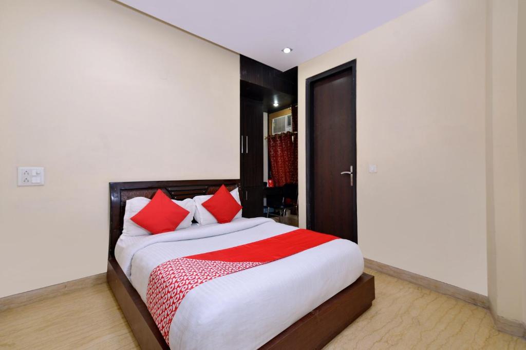 a bedroom with a large bed with red pillows at OYO Capital O Hotel Lotus B&B in New Delhi