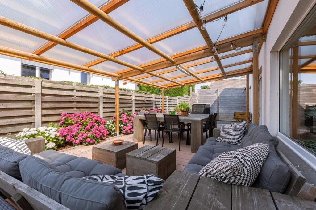 a patio with a couch and a table and a pergola at Spacious house with garden and parking in Blankenberge