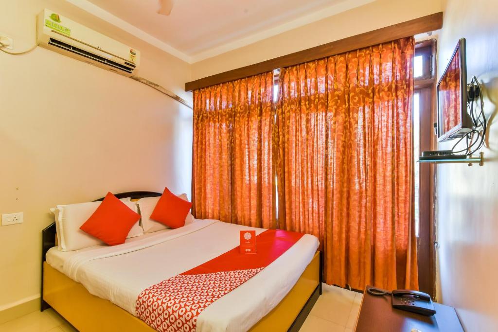 a bedroom with a bed and a window with orange curtains at Hotel Pillar'S Near Immaculate Conception Church in Old Goa