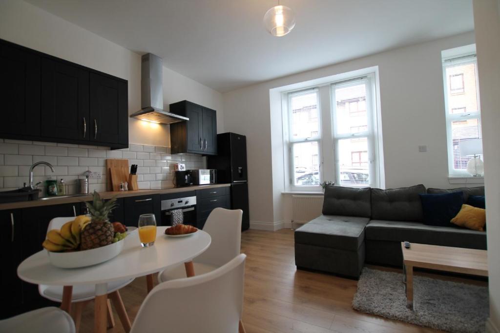 Superb One Bedroom Apartment in Dundee في دندي: مطبخ وغرفة معيشة مع طاولة وأريكة
