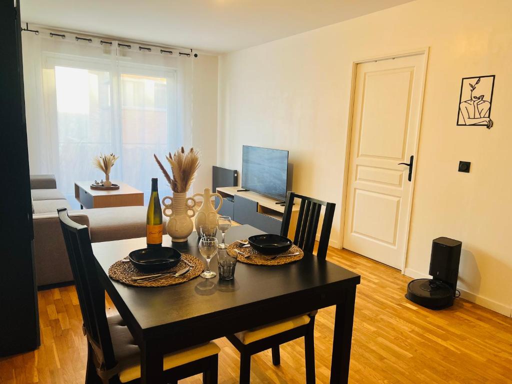 une salle à manger avec une table avec des chaises et une télévision dans l'établissement Appartement proche de Paris, à Alfortville