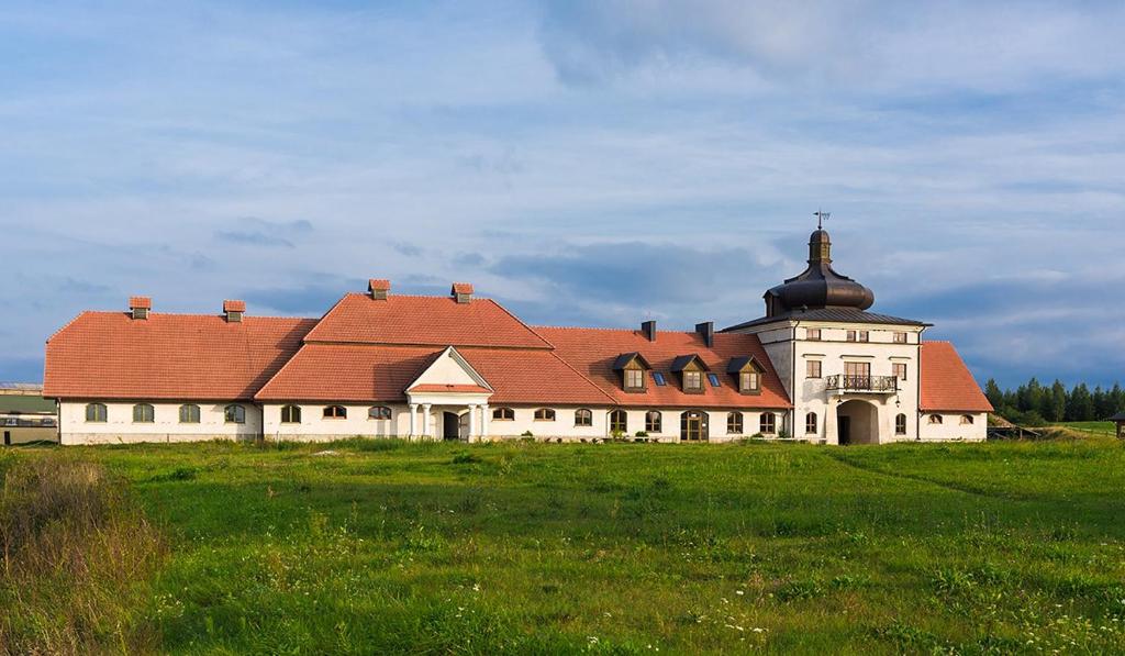 een groot gebouw met een rood dak in een veld bij Stadnina Koni Nad Wigrami in Mikolajewo