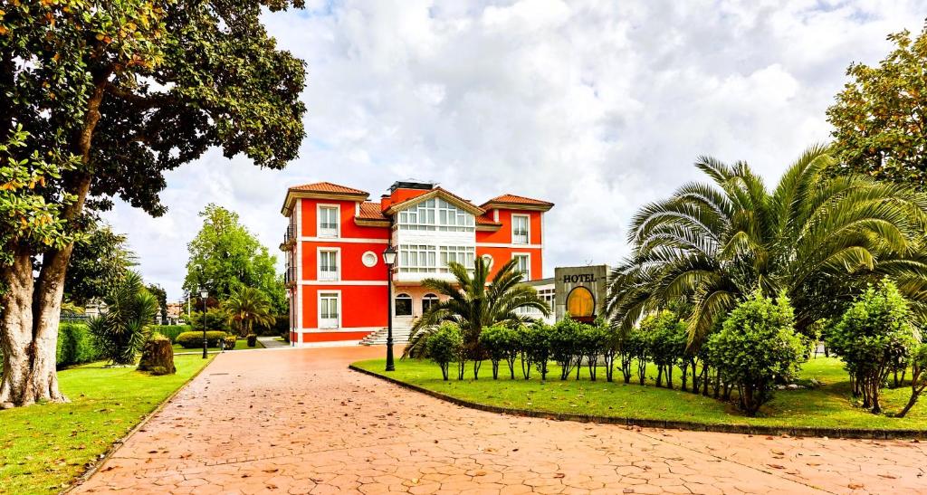 una casa roja con árboles delante de ella en Silken Spa La Hacienda De Don Juan en Llanes