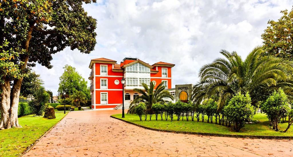 una casa rossa con alberi di fronte di Silken Spa La Hacienda De Don Juan a Llanes