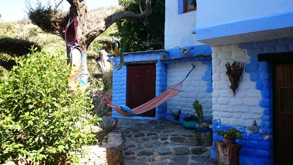 una casa azul con una hamaca delante en Alojamiento Rural El Brazal, en Lanjarón