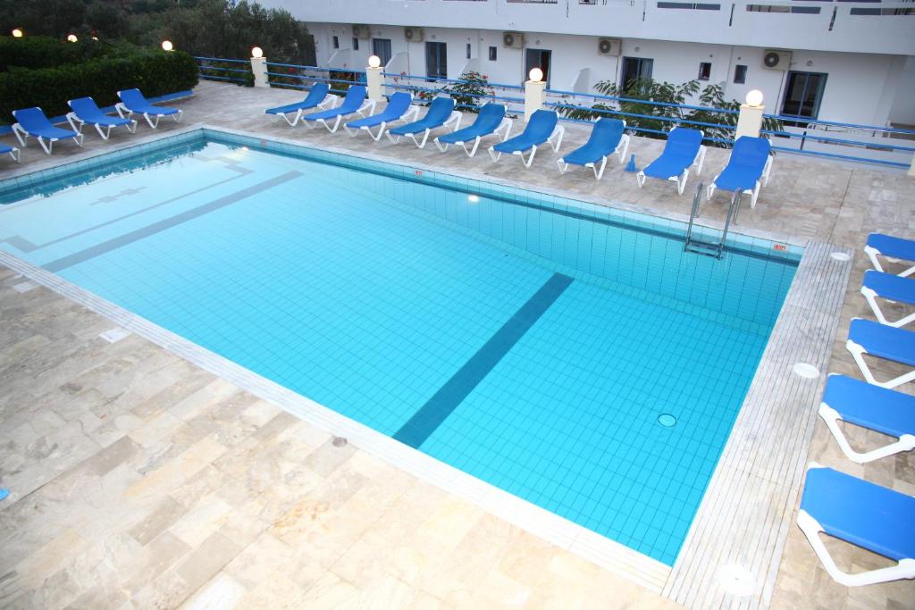 an overhead view of a swimming pool with blue chairs and a hotel at Poseidon Hotel in Amoudara Herakliou