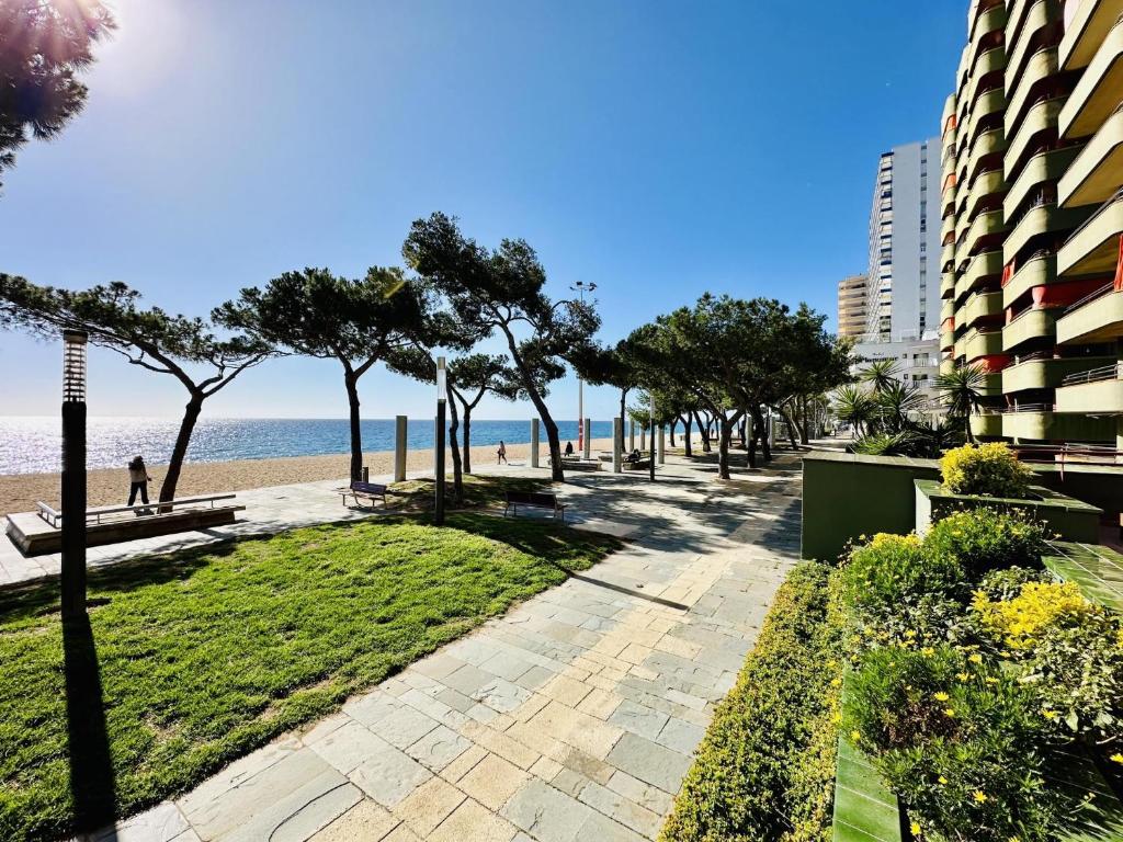 una pasarela junto a una playa con árboles y edificios en Apartament mar i vent, en Platja d'Aro