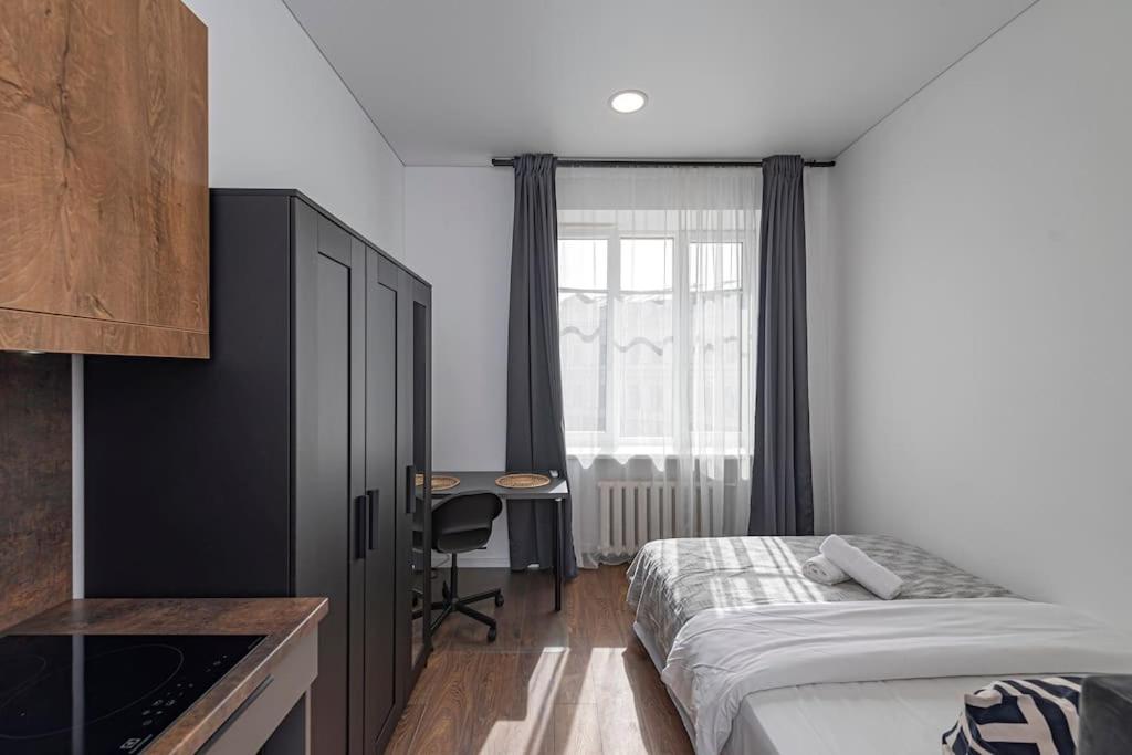 a bedroom with a bed and a desk and a window at Minimalist Studio Apartments by Hostlovers in Kaunas