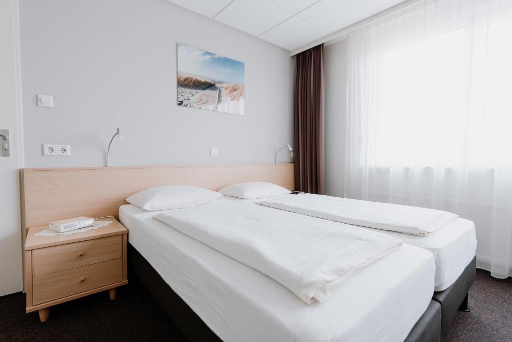 - une chambre avec 2 lits et une table de nuit dans l'établissement Hotel Kodde, à Aagtekerke