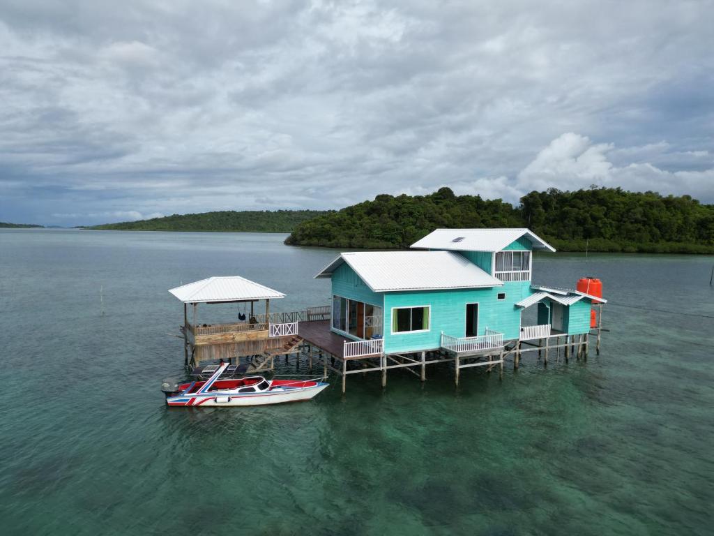 a house on a dock in the water with a boat at Selambak Homestay in Tarempah