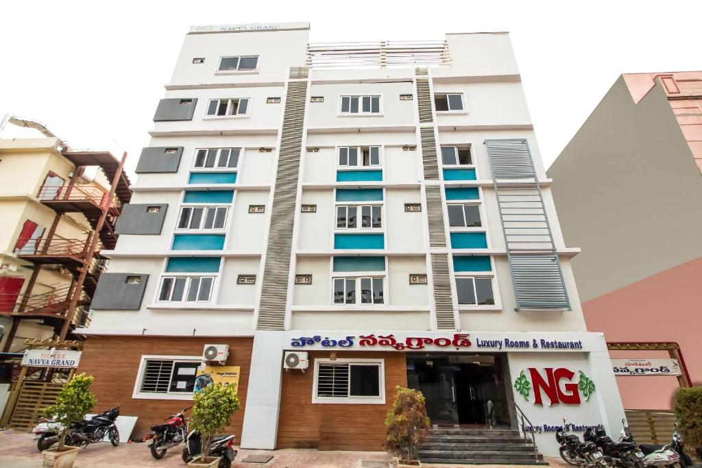 een wit gebouw met een bord ervoor bij Capital O Sri Navya Grand Near Nexus Hyderabad in Lingampalli