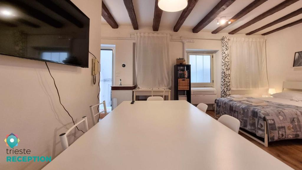 トリエステにあるCasa Valdの白い大きなテーブルとベッドが備わる客室です。