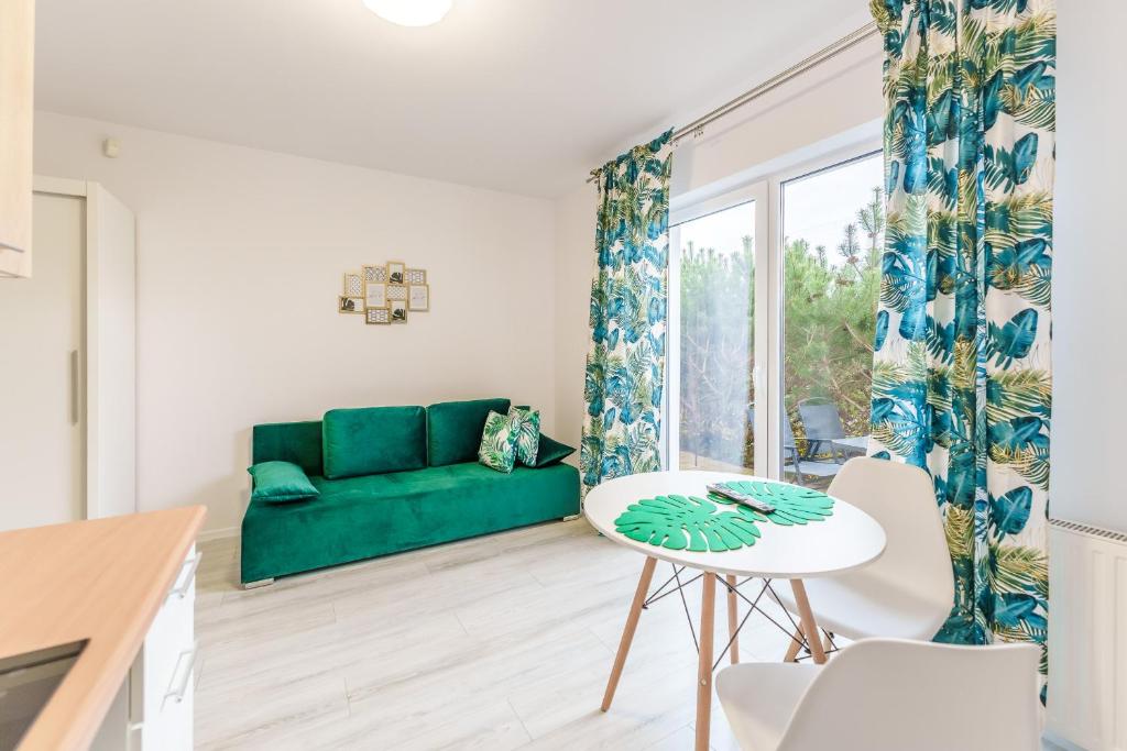 a living room with a green couch and a table at Apartament Tropikalny by Holiday&Sun in Grzybowo