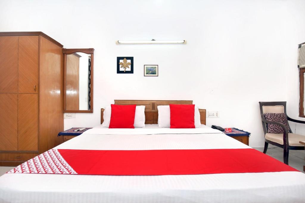 a bedroom with a large bed with red pillows at Hotel Queensland in Amritsar