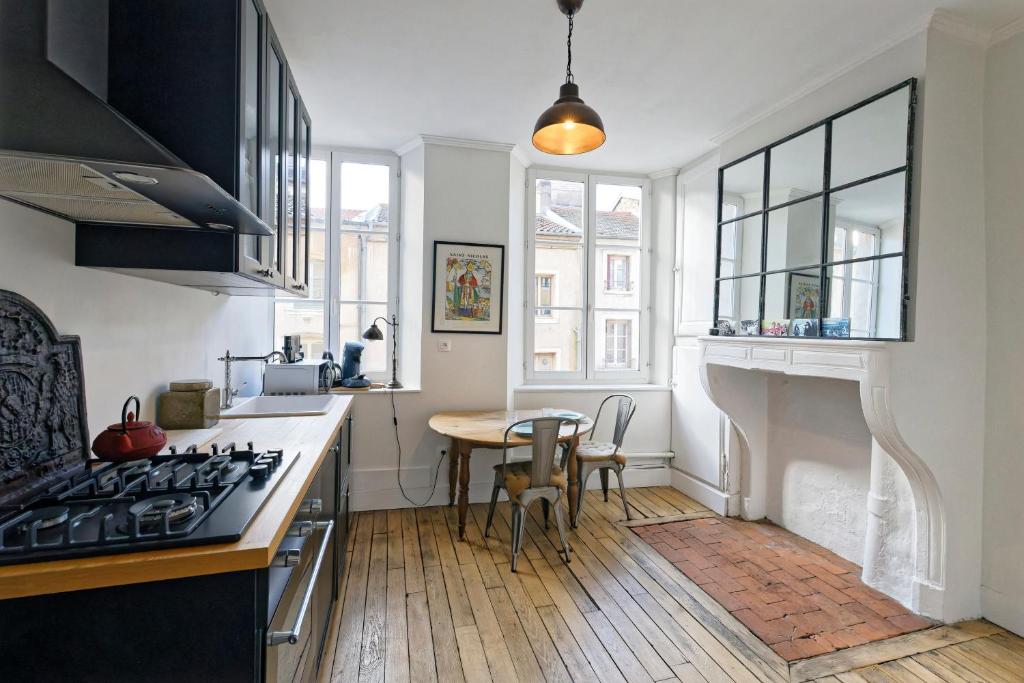 Il comprend une cuisine équipée d'une cuisinière. four supérieur à côté d'une table dans l'établissement Le Boudoir de Stanislas - Appt au cœur de Nancy, à Nancy