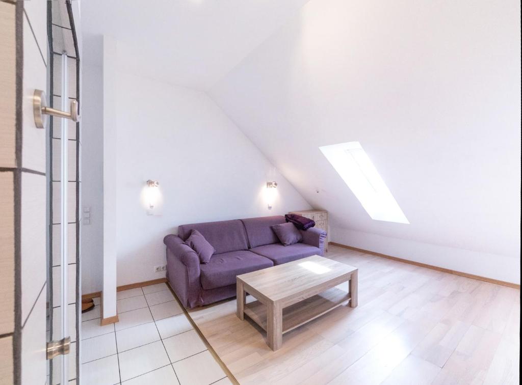 a living room with a purple couch and a table at Revalia Airport-Bus station Studio in Tallinn