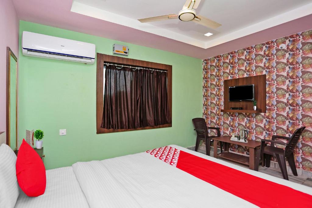 a bedroom with a bed and a table and a television at Capital O Hotel Aryan in Khandagiri