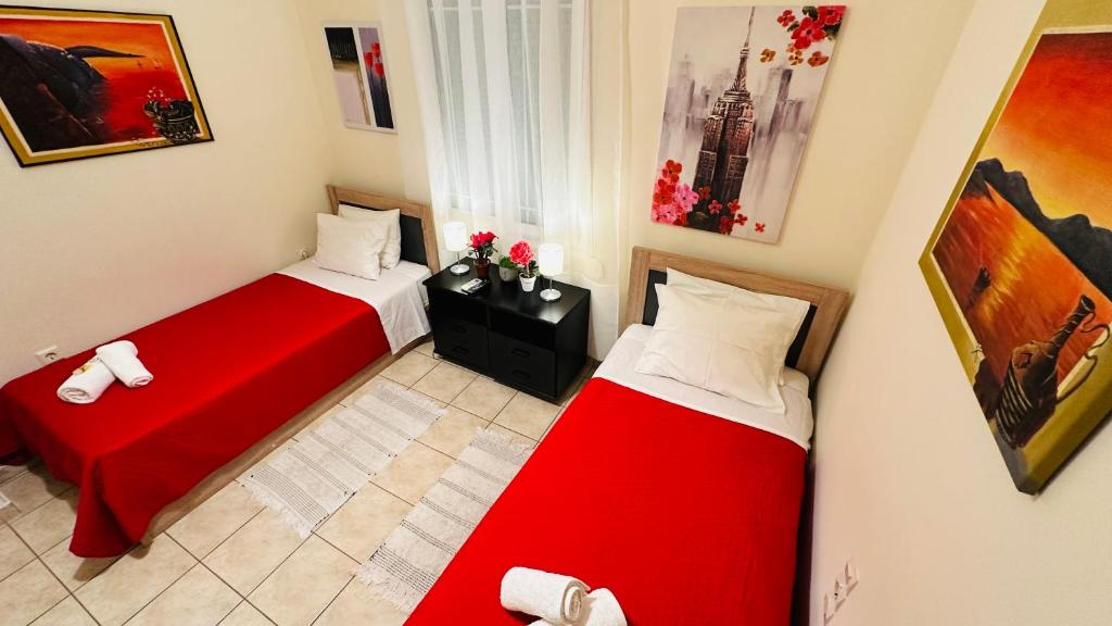 two beds in a small room with red sheets at Patras Centre Apartment in Patra