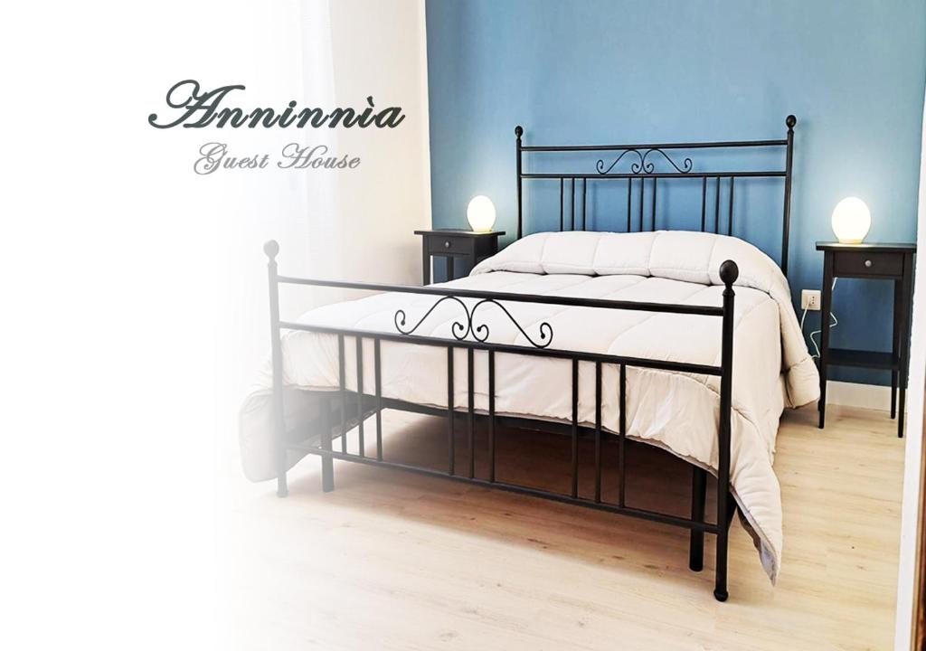 una camera da letto con un letto nero con lenzuola bianche di Anninnìa Guest House B&B - GhiIarza a Ghilarza