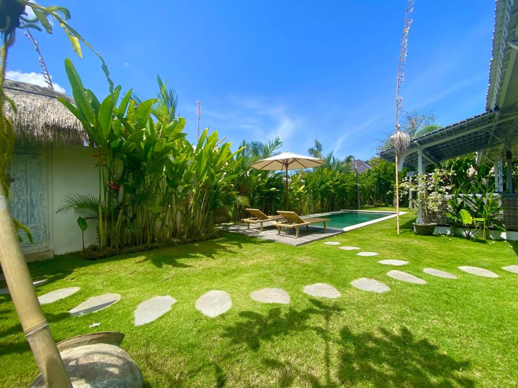einen Hinterhof mit einem Pool und einem Rasenplatz in der Unterkunft Vicolo ArtVillas in Uluwatu